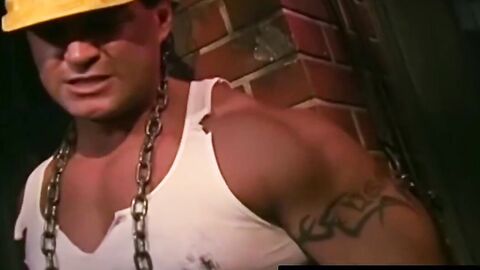 Tattooed man in uniform stuck in tight metal chains