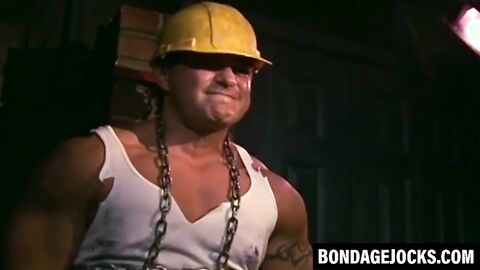 Tattooed man in uniform stuck in tight metal chains