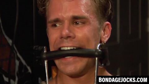 Hunk in bondage gear dominated by his buff partner