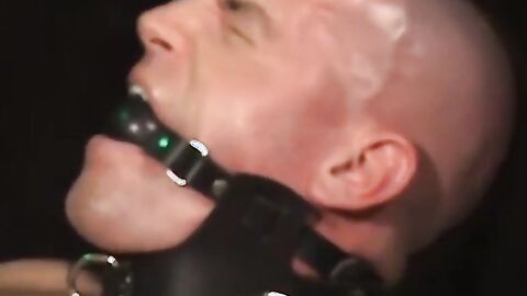 Bigg Pete's neck and mouth strapped in tight leather bondage