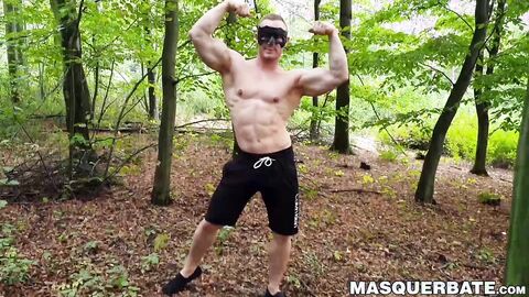 Muscular dude strokes his cock outdoors while wearing a mask