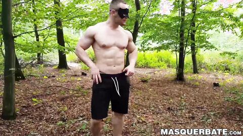 Muscular dude strokes his cock outdoors while wearing a mask