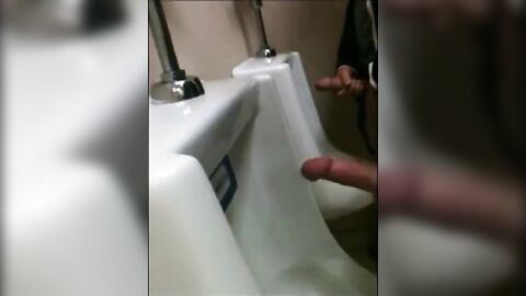 two slim dicks getting wanked at the urinals