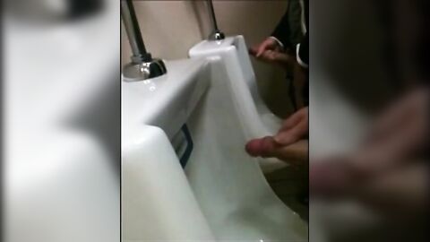 two slim dicks getting wanked at the urinals