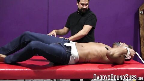 Kaden Roads enjoys slapping the captive with a flogger before playing with his cock